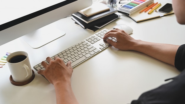 Bovenaanzicht man handen met behulp van computer op kantoor aan huis met bijgesneden schot.