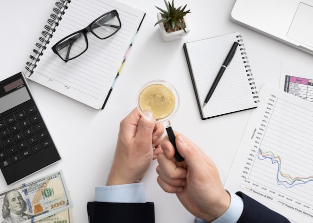 Foto bovenaanzicht man kijken naar een muntstuk met een vergrootglas