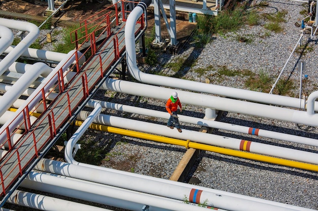 Bovenaanzicht mannelijke werknemer inspectie bij stalen lange pijpen en pijp elleboog ventiel in station oliefabriek tijdens raffinaderij klep van visuele controle record pijpleiding olie