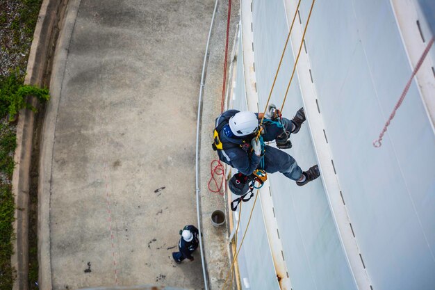 Bovenaanzicht mannelijke werknemer inspectie dragen van de eerste veiligheidsharnas touw veiligheidslijn werken op een hoge plaats op het tankdak bolvormig