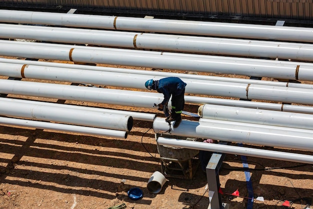 Bovenaanzicht mannelijke werknemer stalen lange buizen en pijp elleboog nieuwbouw olietank van laspijpleiding olie- en gasindustrie