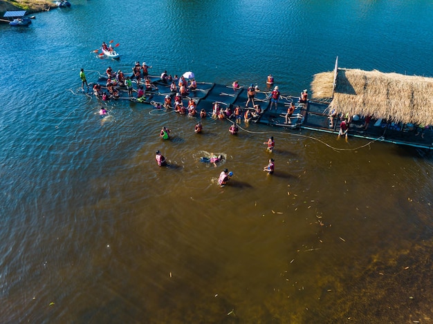 Bovenaanzicht Mensen spelen water in de buurt van een houten vlot dat op de rivier de chanaburi Thailand drijft