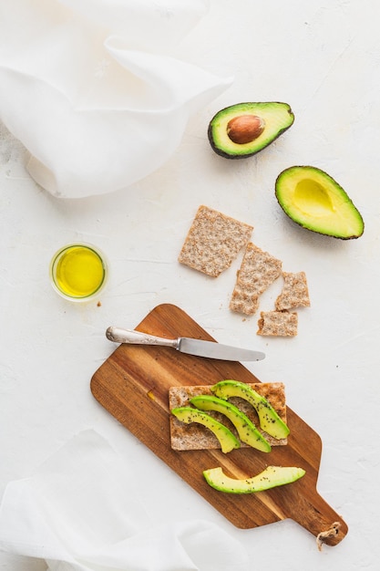 Foto bovenaanzicht met gezonde toast met avocado op een houten bord op witte achtergrond