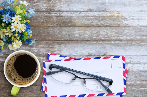 Bovenaanzicht met luchtpost envelop kopje koffieglazen en bloem op houten tafel achtergrond