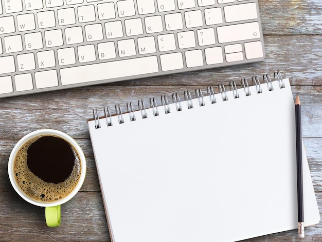 Bovenaanzicht met notebookpencilkeyboard en koffie op houten tafel achtergrond