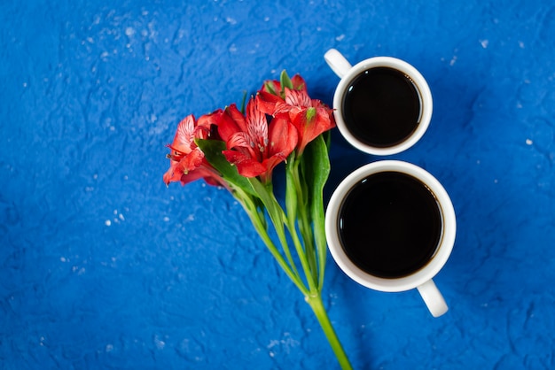 Bovenaanzicht met twee kopjes koffie met rode bloem op de kopie ruimte.