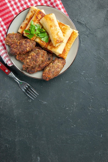 Bovenaanzicht met vlees gevulde blini en schnitzels op ronde plaatvork op tafelkopieerplaats