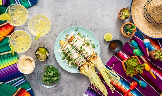 Bovenaanzicht. Mexicaans straatgraan elote grillen gegarneerd met kruiden op een serveerschaal.