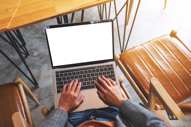 Bovenaanzicht mockup afbeelding van een vrouw die gebruikt en typt op een laptopcomputer met een leeg wit desktopscherm