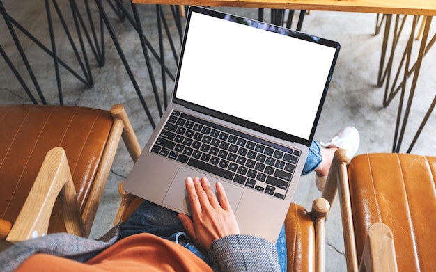 Bovenaanzicht mockup afbeelding van een vrouw die het touchpad van een laptopcomputer gebruikt en aanraakt met een leeg wit desktopscherm