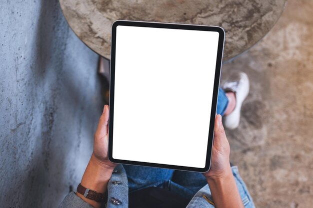 Bovenaanzicht mockup afbeelding van een vrouw met een digitale tablet met een leeg wit bureaubladscherm