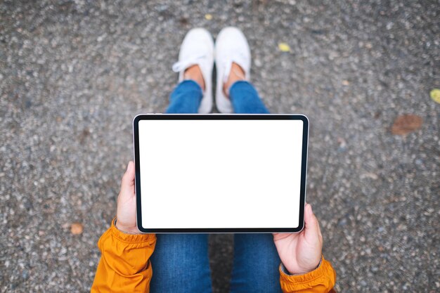 Bovenaanzicht mockup afbeelding van een vrouw met een digitale tablet met een leeg wit desktopscherm in de buitenlucht