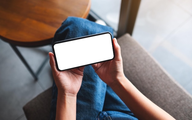 Foto bovenaanzicht mockup afbeelding van een vrouw met een mobiele telefoon met een leeg wit desktopscherm