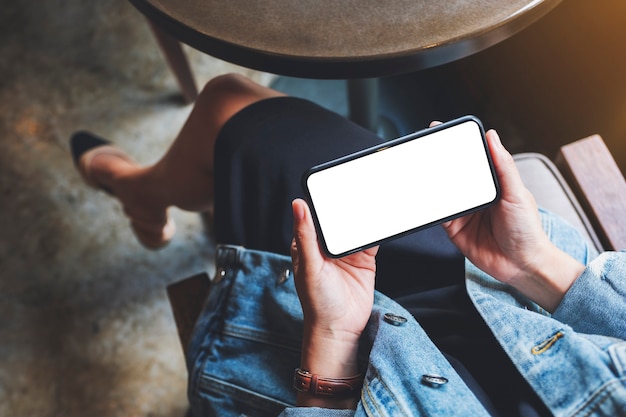 Bovenaanzicht mockup afbeelding van een vrouw met zwarte mobiele telefoon met leeg scherm