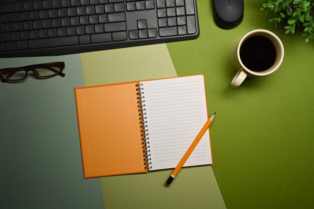 Bovenaanzicht notebook glazen koffiekopje en kamerplant op groene achtergrond