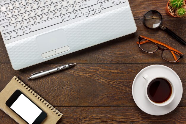 Bovenaanzicht notitieblok, pen, cactus, horloge, mobiele telefoon, Laptop, koffie op kantoor bureau achtergrond.