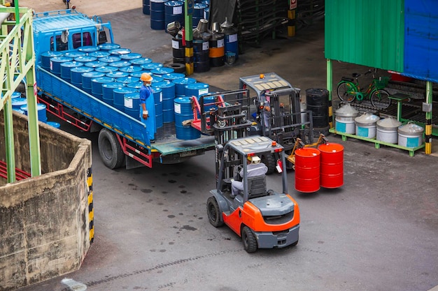 Bovenaanzicht olievaten vorkheftruck verplaatsen voor op de transportwagen mannelijke werknemer help