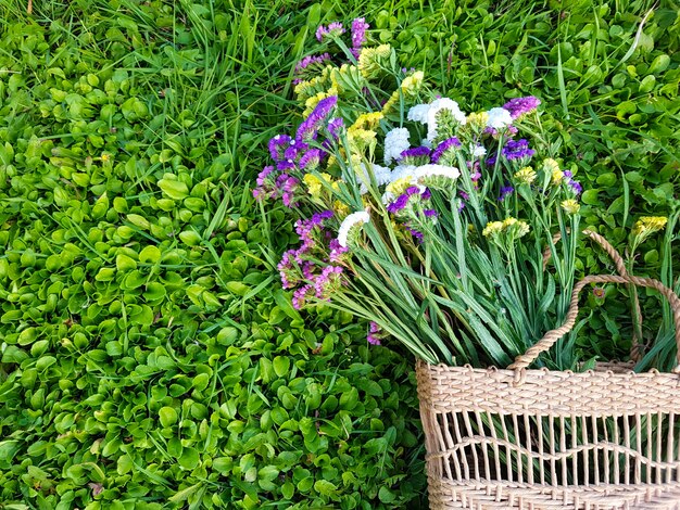 Bovenaanzicht op een boeket bloemen in een stro vrouwen tas op een achtergrond van gras