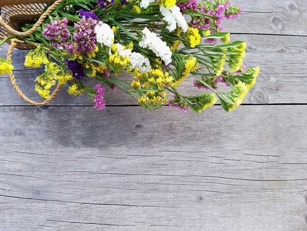 Bovenaanzicht op een boeket bloemen in een zak van stro vrouwen op een achtergrond van houten planken