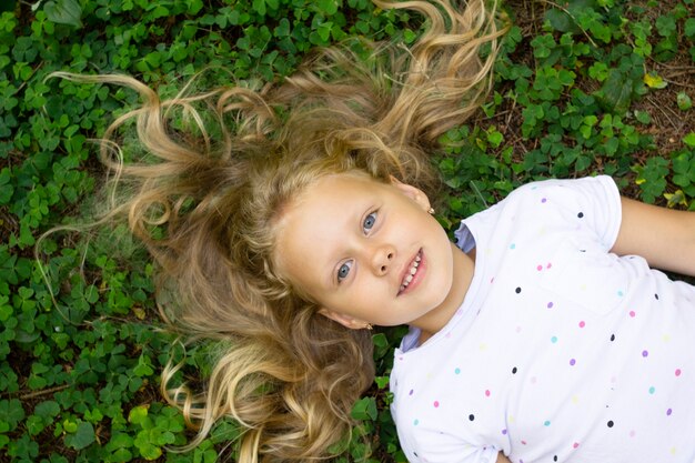 Bovenaanzicht op meisje met blond haar op groen gras