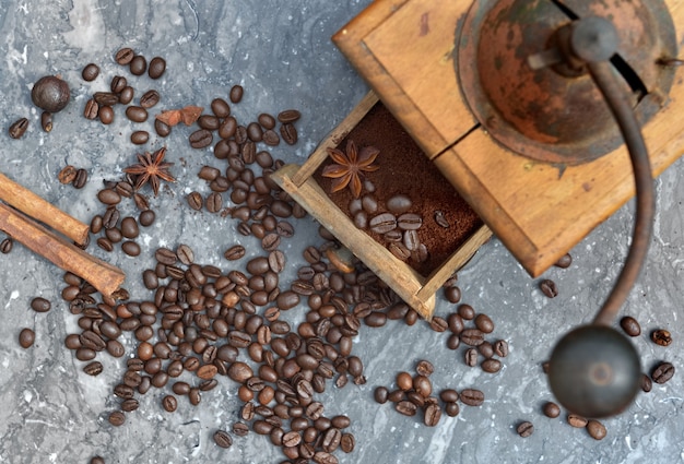 Bovenaanzicht op oude koffiemolen vol koffie en bonen met kruiden op grijs marmer hebben