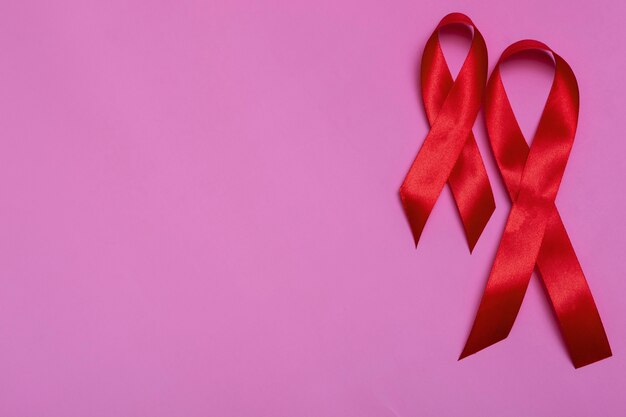 Bovenaanzicht op roze achtergrond met rood lint concept 1 december International AIDS Day close-up.