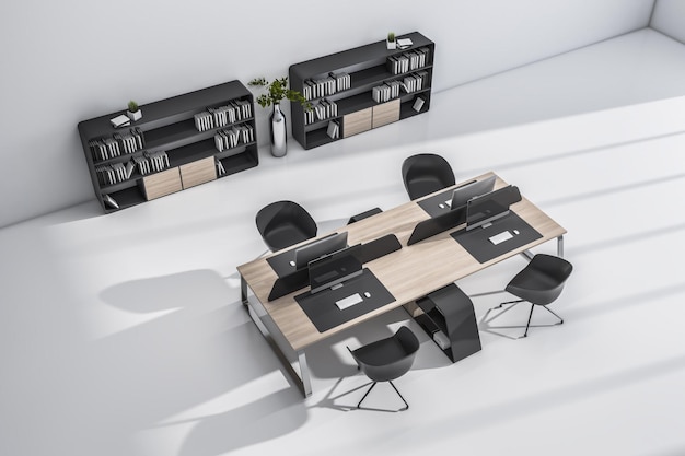 Foto bovenaanzicht op stijlvolle werkruimten met houten tafels, zwarte stoelen, moderne computers en donkere planken op lichte vloer 3d-rendering