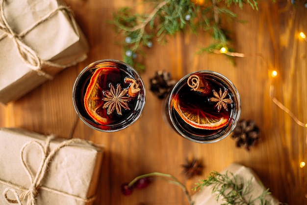 Bovenaanzicht op twee glazen mokken glintwine met ambachtelijke cadeautjes en guirlande lichten op de houten tafel