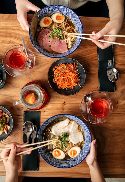 Bovenaanzicht op twee mensen eten Japanse ramen noodlesoepen en andere Aziatische gerechten