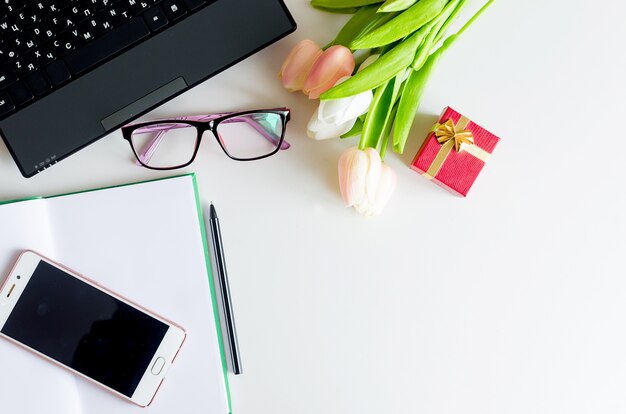 Bovenaanzicht op werkplek met cadeau en bloemen