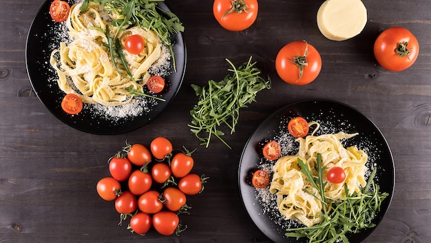 Bovenaanzicht op zwarte borden met pasta op een houten bord