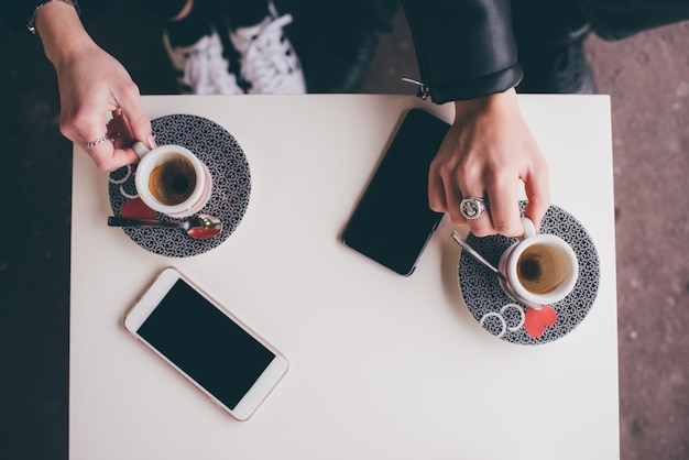 Bovenaanzicht paar jonge volwassenen koffie drinken met telefoon