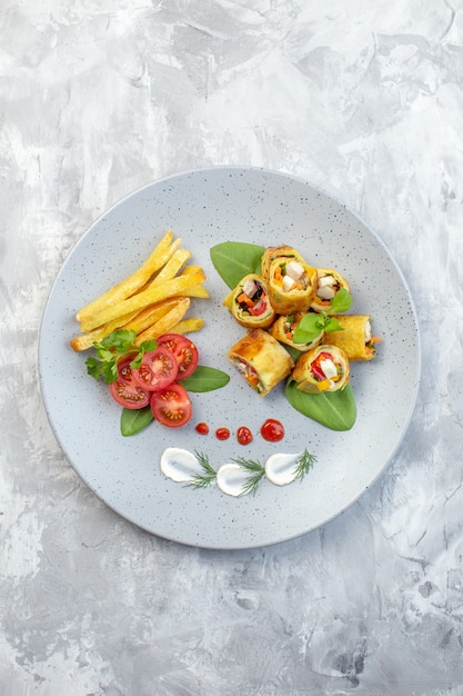 Bovenaanzicht plantaardige patérolletjes met tomaten en frietjes in plaat op witte ondergrond