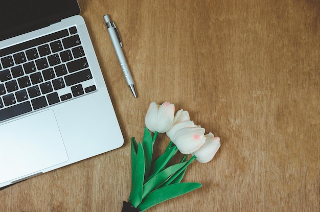 Bovenaanzicht plat lag computer laptop en bloem op houten tafel. Kopieer ruimte