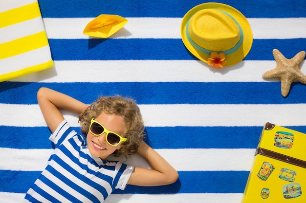 Foto bovenaanzicht portret van kind op gestreept strandlaken zomervakantie concept