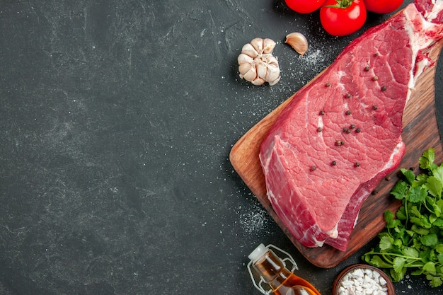 Bovenaanzicht rauw vleesplak met greens en tomaten