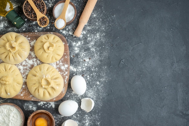 bovenaanzicht rauwe dumplings over snijplank met bloem en eieren