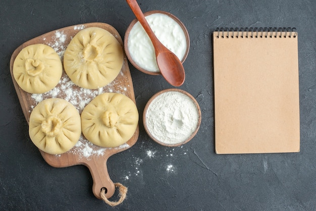 bovenaanzicht rauwe dumplings over snijplank met bloem