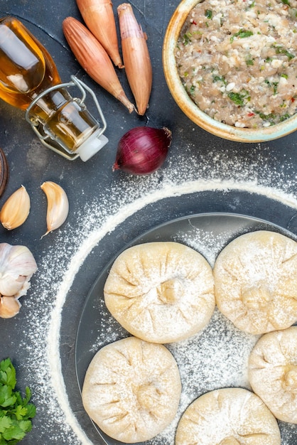 Bovenaanzicht rauwe kleine knoedels met verschillende ingrediënten op een donkergrijze achtergrondvoedseltaartcake, kook smakelijk vleesmeel, bak deegkleur