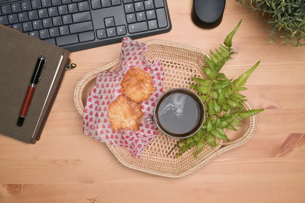 Bovenaanzicht rieten mand met koekjes en koffiekopje op houten tafel