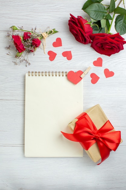 bovenaanzicht rode rozen met notitieblok en cadeau op witte achtergrond liefde vakantie passie minnaar paar huwelijk hart gevoel opmerking