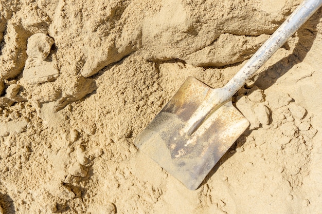 Bovenaanzicht schop op zand in bouwplaats