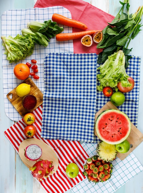 Bovenaanzicht shot van verschillende gezonde smakelijke voedzame verse rauwe natuurlijke biologische landbouw veganistische groenten en fruit ingrediënt dieet geplaatst op snijplank en kleurrijke geruite servetten achtergrond.