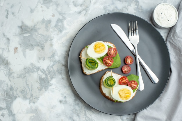 bovenaanzicht smakelijke eiersandwiches met mes en vork binnen plaat witte achtergrond sandwich dieet lunch toast voedsel gezondheid hamburger maaltijd