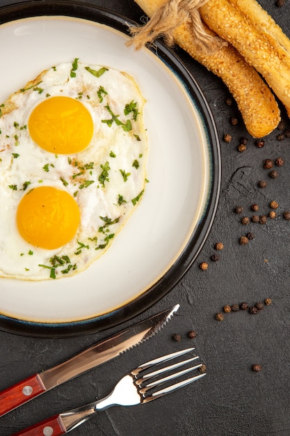 bovenaanzicht smakelijke omelet met vork en mes op donkere achtergrond brood lunch ei kook ontbijt omelet eten