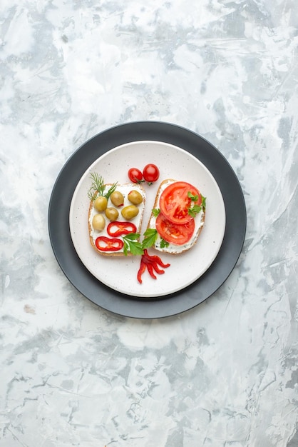 Bovenaanzicht smakelijke sandwiches met tomaten en olijven in plaat witte achtergrond brood eten lunch horizontale maaltijd toast hamburger sandwich