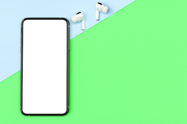 Bovenaanzicht smartphone leeg scherm sjabloon en oortelefoon op pastel achtergrond