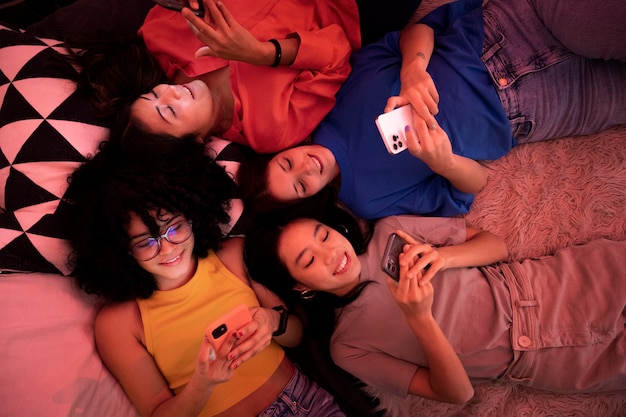 Foto bovenaanzicht smiley vrouwen in bed met smartphones