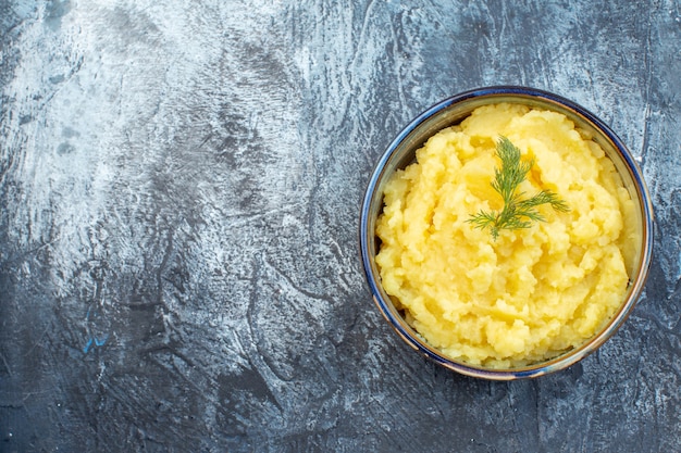 Bovenaanzicht van aardappelpuree geserveerd met dille aan de linkerkant op een donkere achtergrond met vrije ruimte