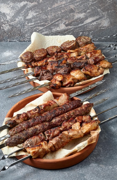 Bovenaanzicht van assortiment van sjasliek en kebab over grijze achtergrond